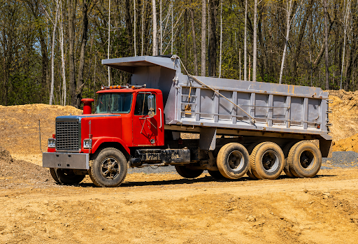 Heavy-duty dump truck on a construction site transporting soil and aggregate, showcasing reliable hauling equipment and durable dump trailer solutions in Carolina.