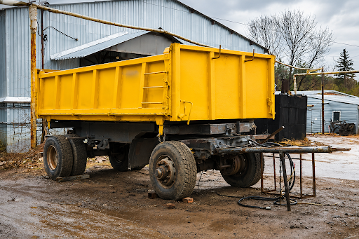 Bright yellow heavy-duty dump trailer parked at an industrial yard, showcasing durable hauling equipment designed for construction, landscaping, and material transport in the Carolinas.